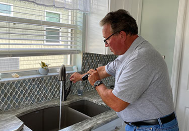 A home inspector checking the kitchen plumbing.